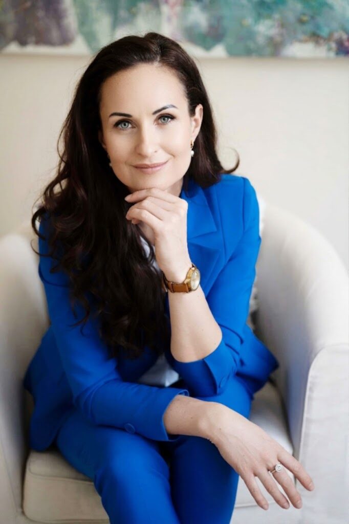 Aurelija Aspen seated in a blue suit, founder and creator of the Energetic Reprogramming Method for releasing subconscious emotional patterns
